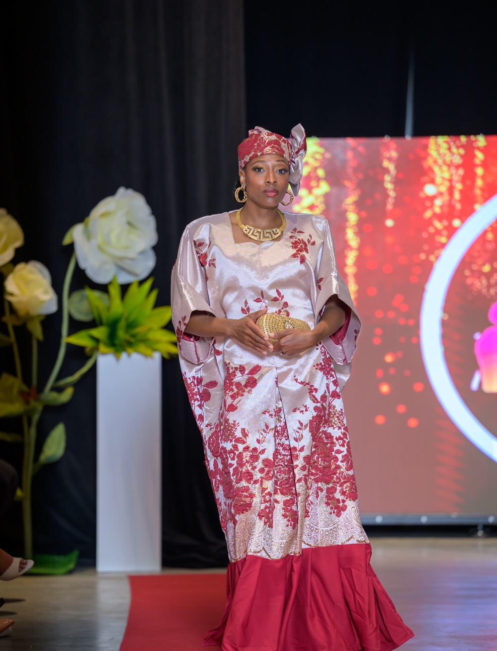 Womenswear look in a silver and deep red floral gown with matching headwrap and gold jewellery, from the Adeyemi RoyaLabel HIFW Season Six runway